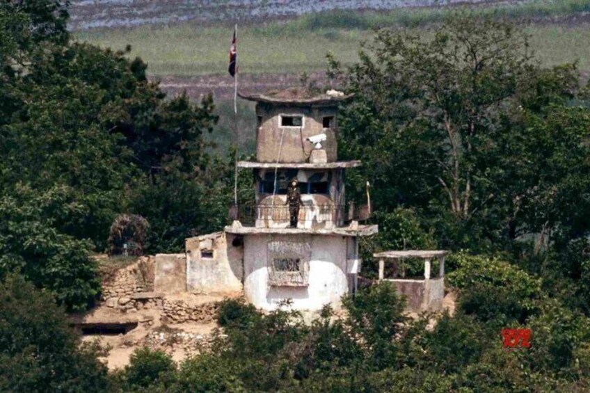 A multi-tiered structure with a flag, surrounded by trees and vegetation. 1