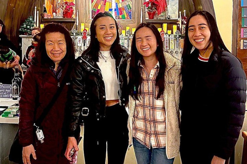Four people standing indoors with a colorful stained glass window in the background. 3