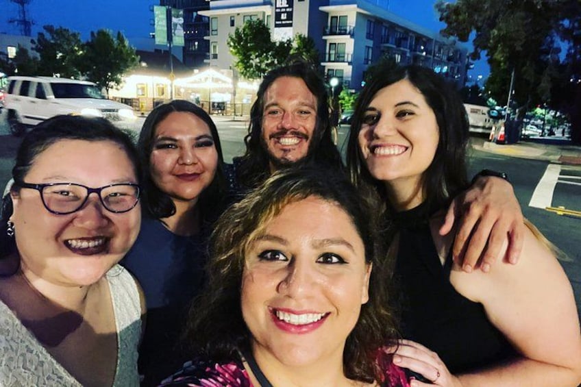 A group of people posing for a photo on a city street at night. 4