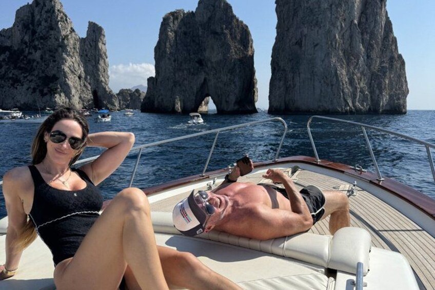 Un bateau avec deux personnes qui se détendent, des falaises rocheuses en arrière-plan et une mer calme. 4