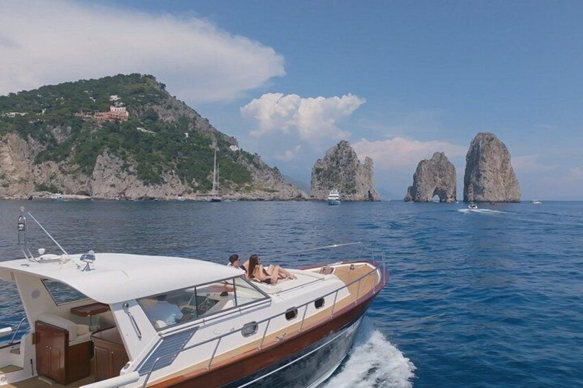 Un bateau sur une étendue d’eau calme, des affleurements rocheux et, au loin, une colline parsemée de bâtiments. 1