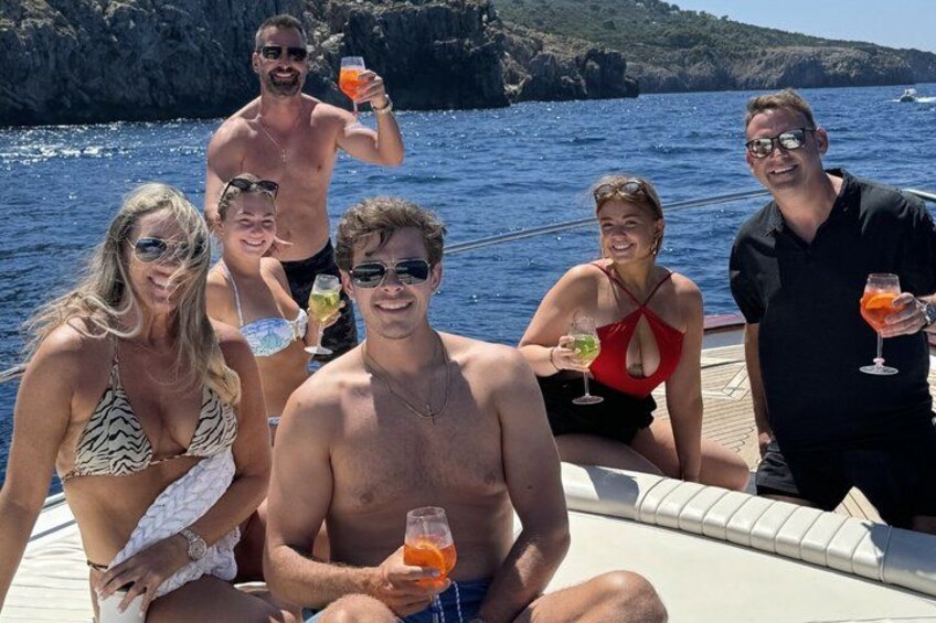 Un groupe de personnes à bord d’un bateau, avec des boissons, une côte rocheuse et une eau d’un bleu cristallin. 5