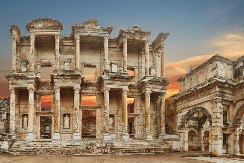Ancient ruins with columns and arches, set against a sunset sky. 1