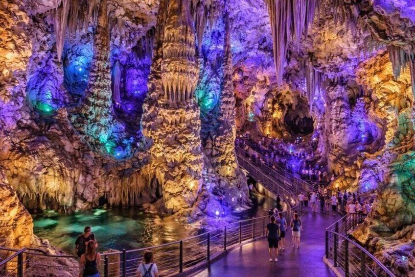 A cave with illuminated stalactites and a walkway for visitors. 4