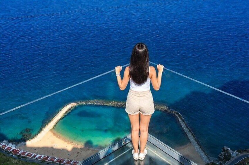 A person standing on a bridge overlooking a beach with clear blue waters. 3