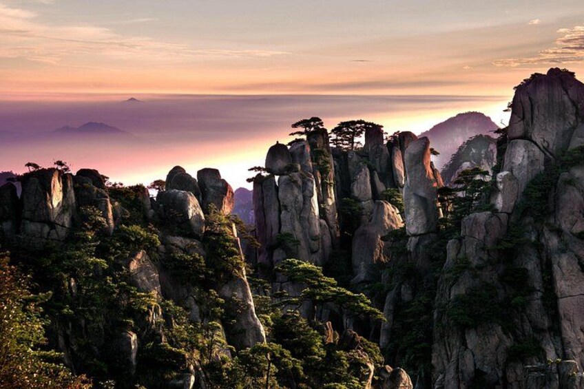 A mountainous landscape with prominent rock formations and dense forest. 2