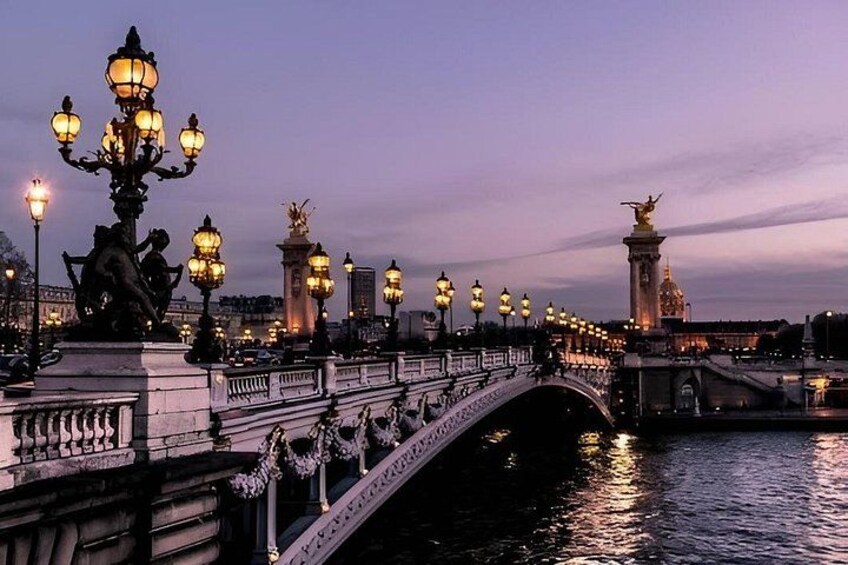 A bridge with ornate lamp posts and statues, reflecting on the water at dusk. 3