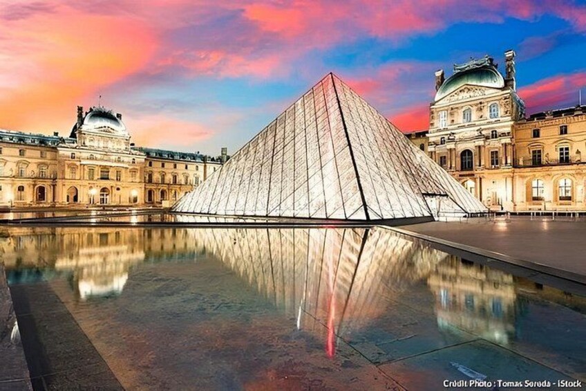 The Louvre Pyramid with its reflection in the water, surrounded by historic buildings. 2