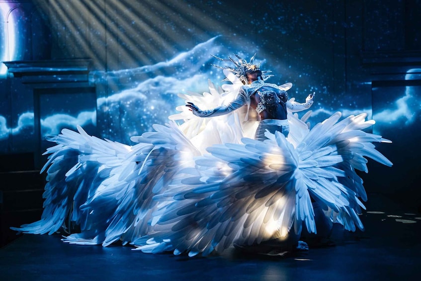 A person in a white, elaborate costume with large, feather-like structures. 1