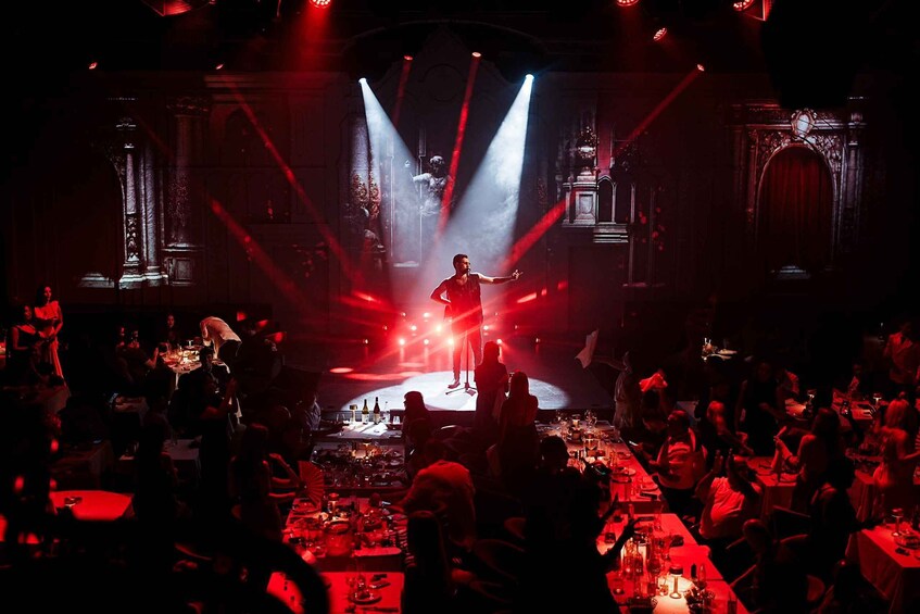 A stage performance with a performer in the center, surrounded by an audience seated at tables. 3