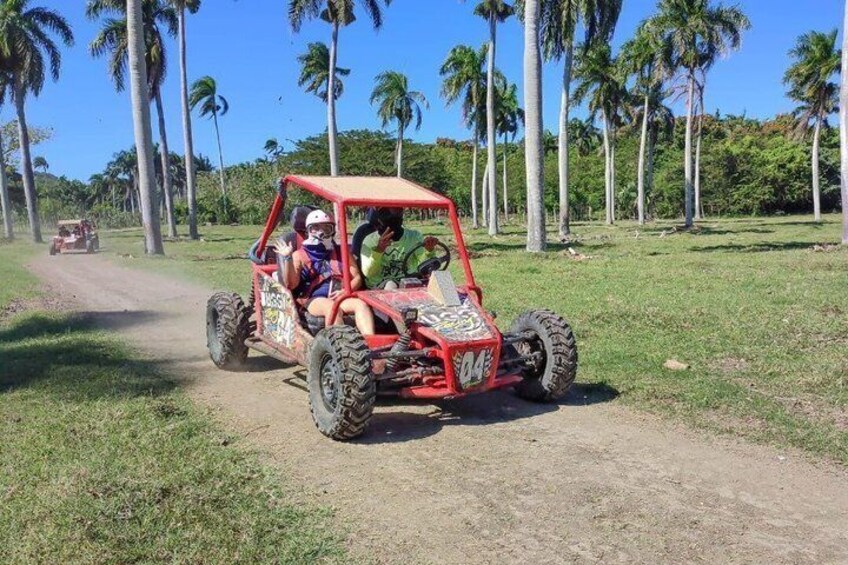 A red off-road vehicle on a dirt path with palm trees in the background. 4