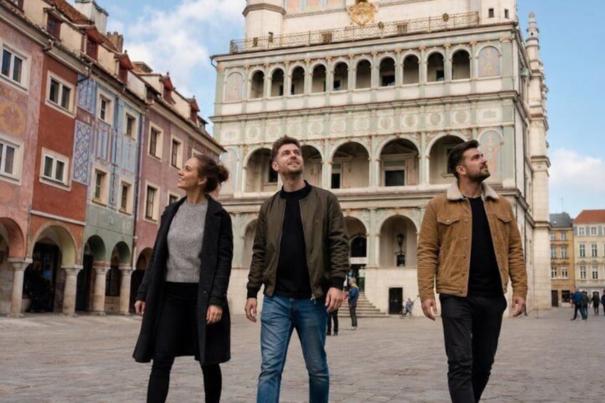 Three people walking in a historic square with ornate buildings in the background. 4