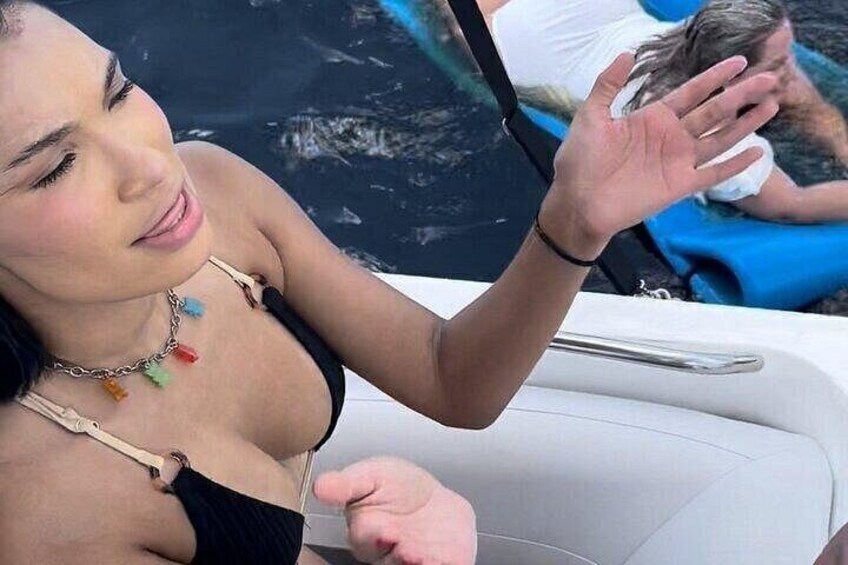 A person in a black swimsuit with colorful beads, sitting in a boat. 2