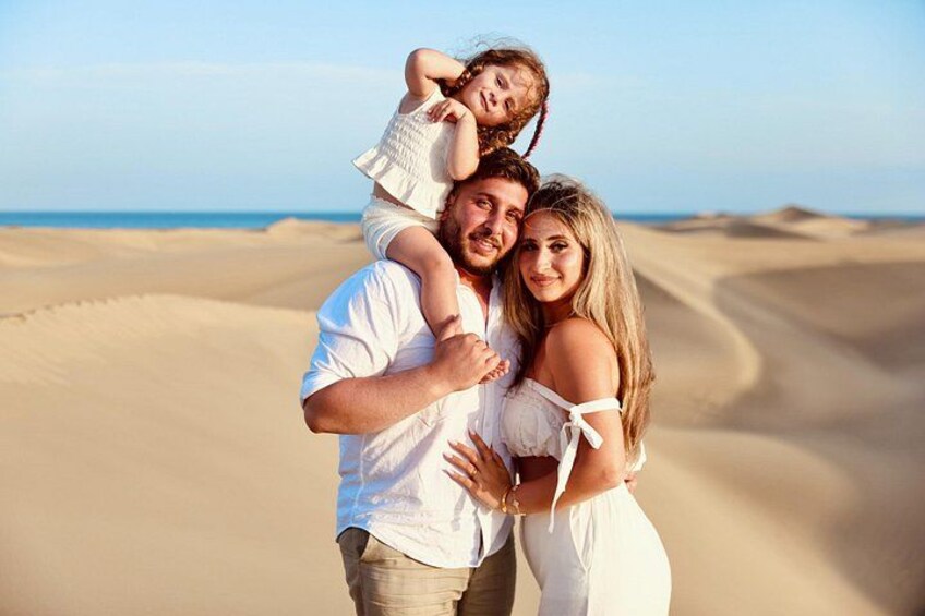 A family on a sandy beach with dunes in the background. 2