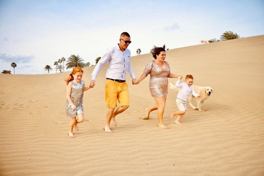 A family running on a sandy beach with palm trees in the background. 5
