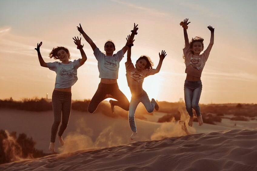 Four people jumping in the air with a sunset in the background. 4
