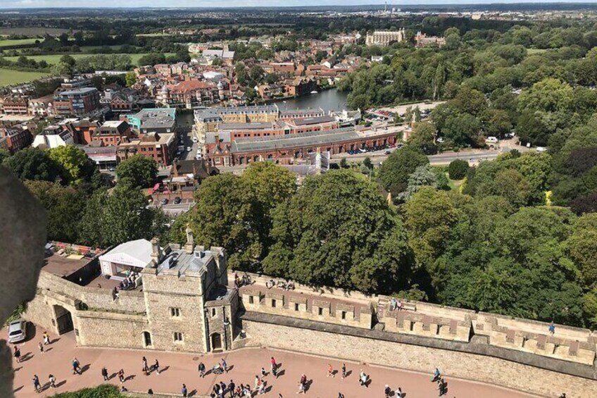 A historic town with a prominent castle, a river, and surrounding greenery. 2