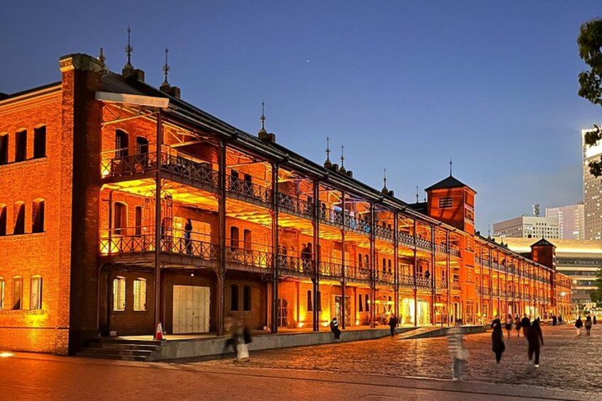 A brightly lit historic building with multiple balconies and a tower, situated on a cobblestone street. 5