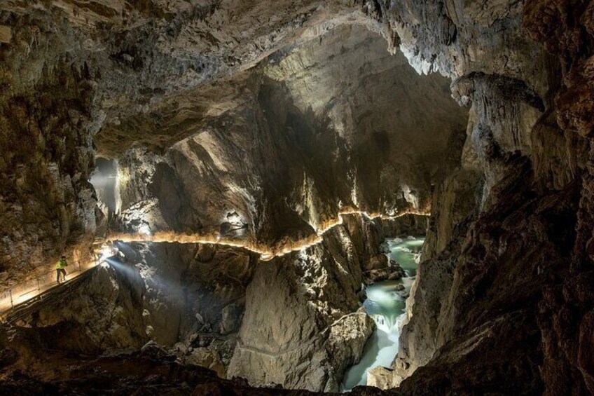 A cave with a river running through it, illuminated by artificial lights. 2
