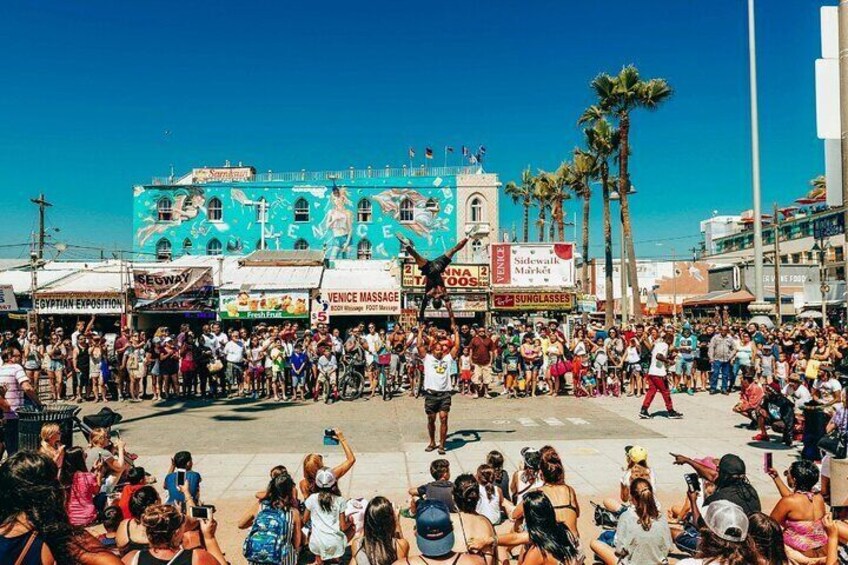 A crowded street with a blue building, palm trees, and various shops. 4