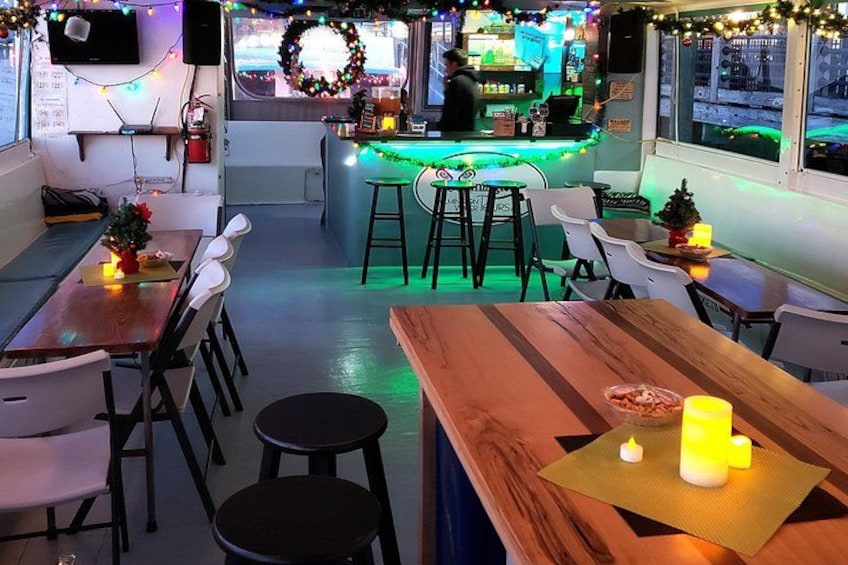 Un comedor interior acogedor con mesas y sillas de madera, una barra con un cantinero y decoraciones festivas. 2