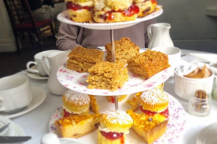A tiered dessert stand with various pastries and a pitcher of cream. 1
