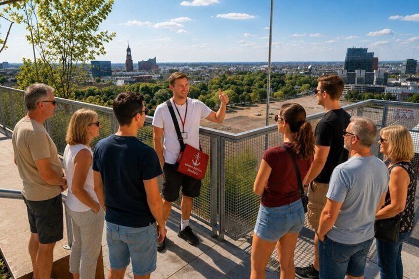A group of people standing on a balcony overlooking a cityscape with a prominent tower. 5