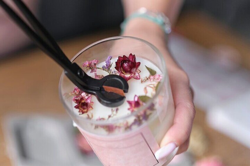 A hand holding a glass with a straw, containing a drink with floral decorations. 3