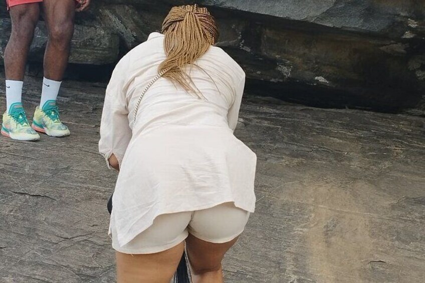 Una persona con camisa y pantalones cortos de pie sobre una superficie rocosa. 4