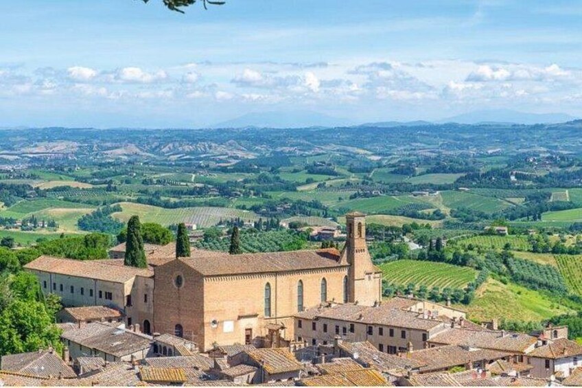A historic town with a prominent church, terraced vineyards, and rolling hills in the background. 5