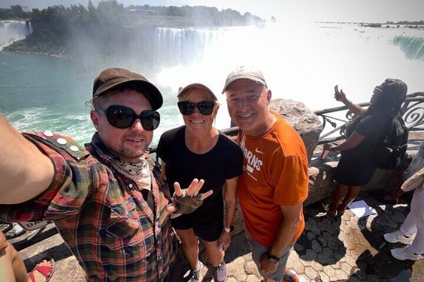 A group of people taking a selfie with a waterfall in the background. 2