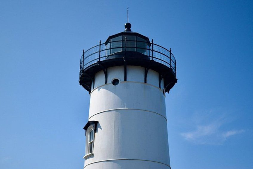 A lighthouse with a white cylindrical tower and a black top. 5