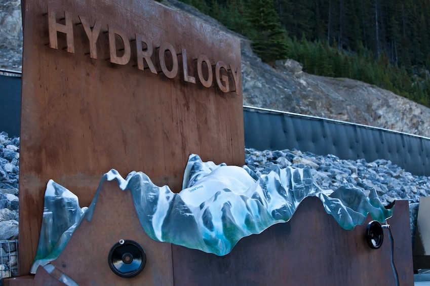 A metal sign with 'HYDROLOGY' and a glass sculpture of a mountain. 4