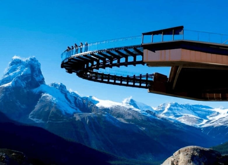 A glass bridge with people walking over a snowy mountain range. 1