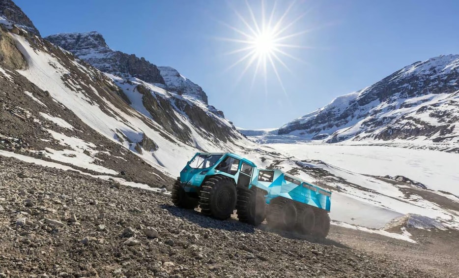 A blue off-road vehicle on a snowy mountain path. 2