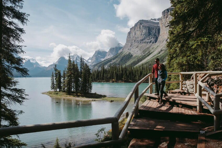 A wooden bridge over a calm lake with mountains in the background. 4