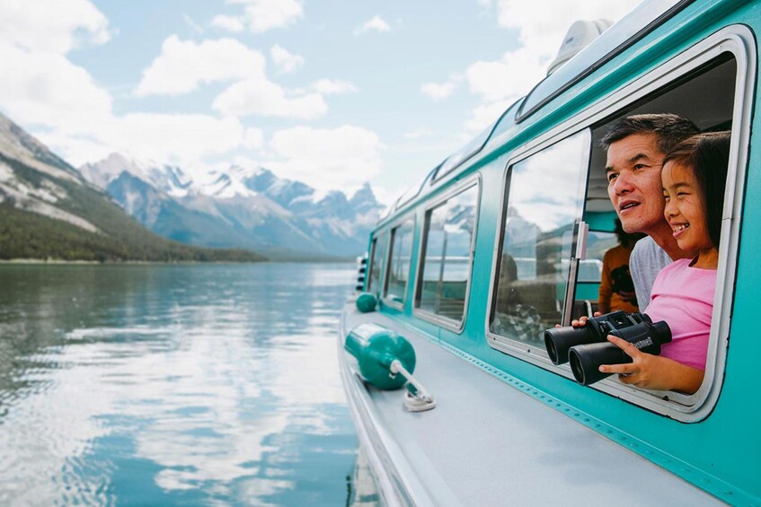 A turquoise boat on a calm lake with mountains in the background. 1