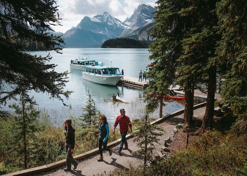 A lake with boats, a dock, and people walking along a path. 5