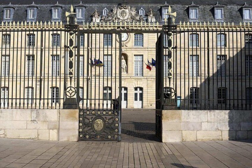 Ein historisches Gebäude mit einem großen schmiedeeisernen Tor, Flaggen und klassischer Architektur. 3