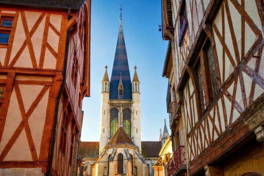 Eine schmale Gasse mit Fachwerkhäusern und einer Kirche mit einem hohen Turm. 1