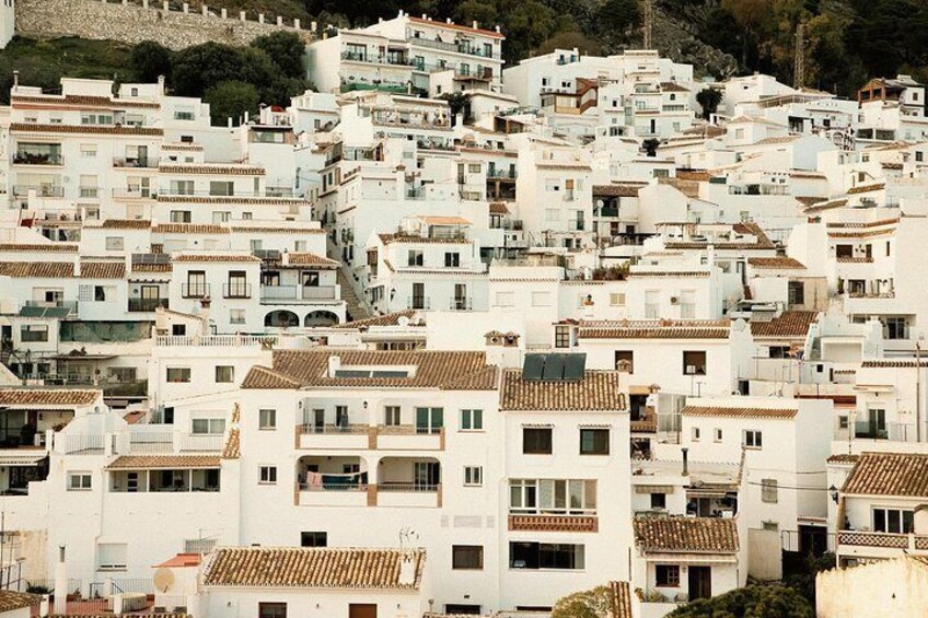 A densely packed hillside of white buildings with terracotta roofs. 2