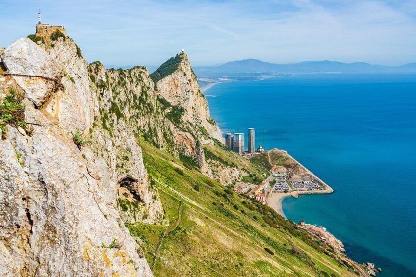 A coastal cliff with a lighthouse, a beach, and a cityscape with tall buildings. 4