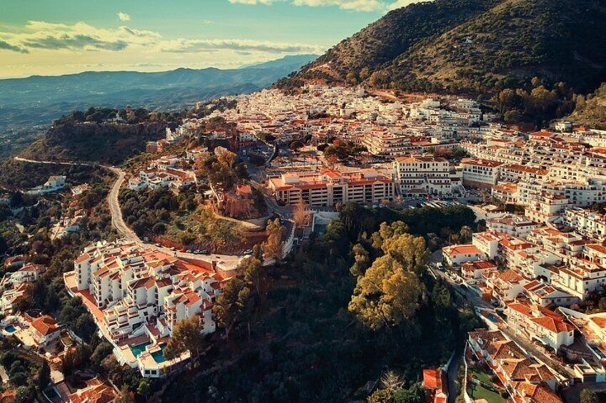 A coastal town with red-roofed buildings, a winding road, and a mountainous backdrop. 3