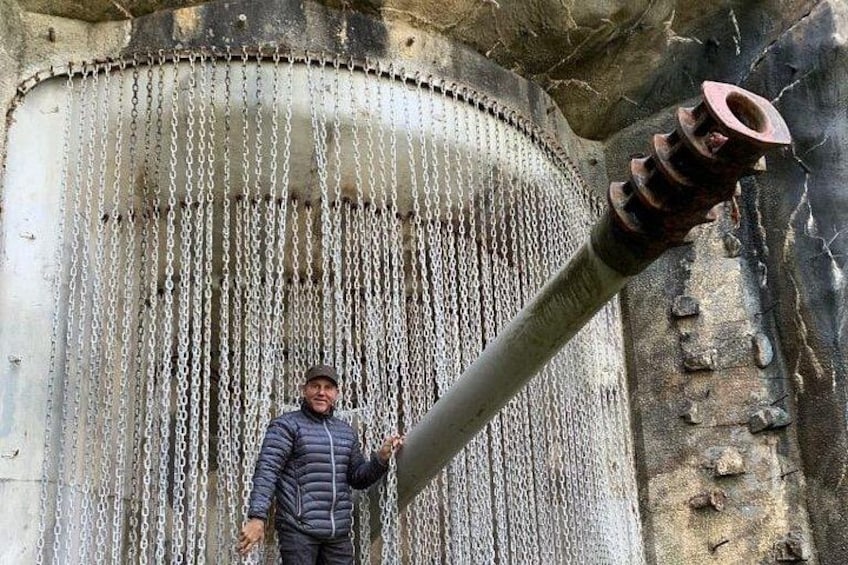 A person standing in front of a large industrial structure with chains hanging from it. 1