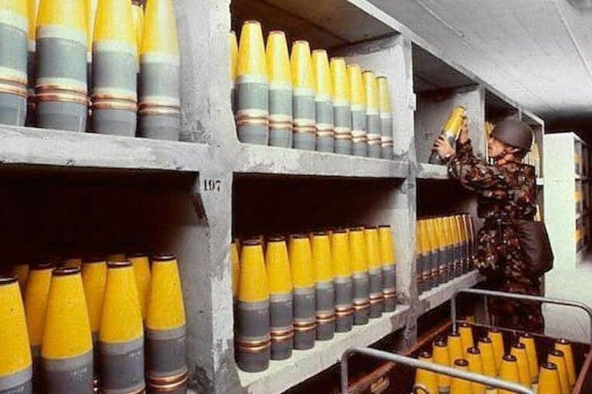 A person in camouflage uniform organizing yellow and gray ammunition in a storage room. 2