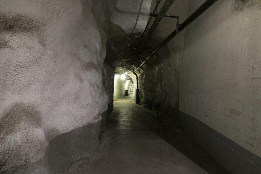 An underground passageway with concrete walls and a light source at the end. 2