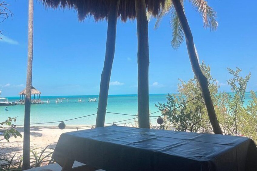A beach with palm trees, a table, and a clear blue sky. 4