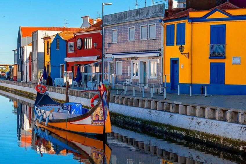 Un canal con un bote colorido, edificios de fachadas vibrantes y un cielo despejado. 3