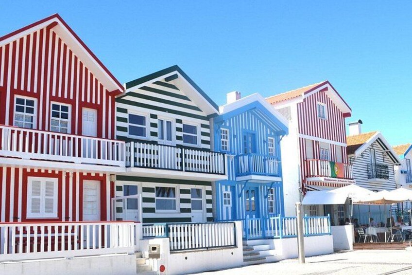 Edificios coloridos con balcones, cielo azul despejado y una valla blanca. 1