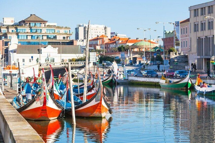 Un puerto con coloridas góndolas amarradas a lo largo del muelle, edificios al fondo y un cielo despejado. 2